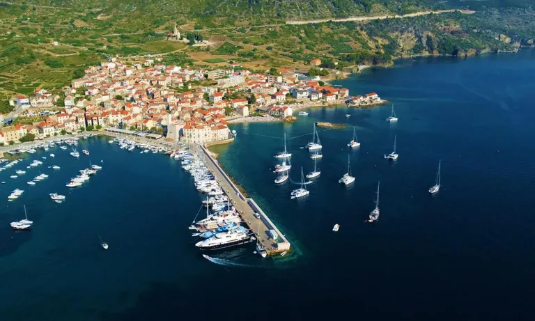 Komiža harbour on Vis island with boats and open Adriatic coastline